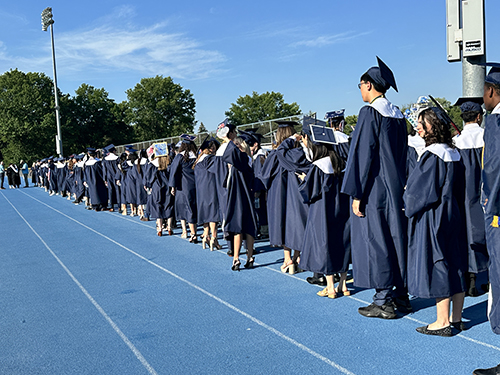 High school graduates lined up on the track before the ceremony