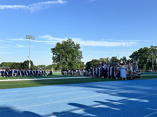 Graduation ceremony with graduates and group of students performing