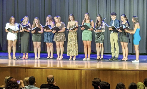 PHS students on stage reading from booklets