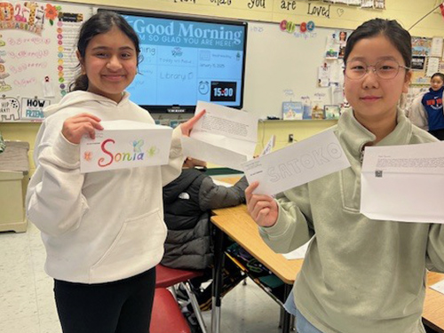 Two High school girls holding up their pen pal letters