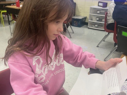 Fourth grade school student reading a letter from her pen pal