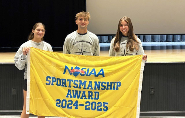 Three happy athletes holding up a sportsmanship banner