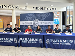 Seven PHS senior athletes sitting at tables to sign commitments